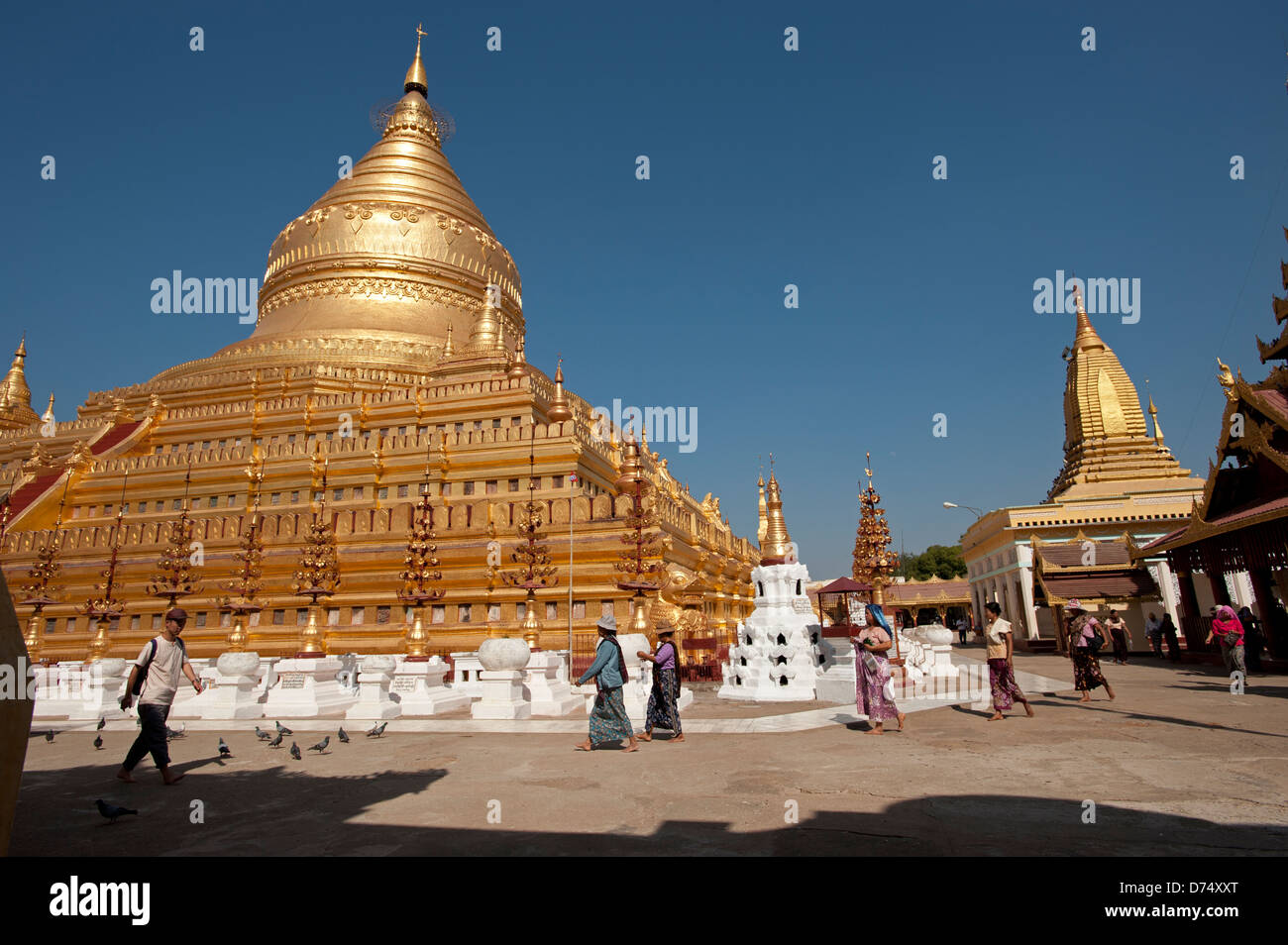 Les habitants de la Birmanie à pied passé le grand dôme d'or de la Pagode Shwezigon Bagan Myanmar (Birmanie) Banque D'Images