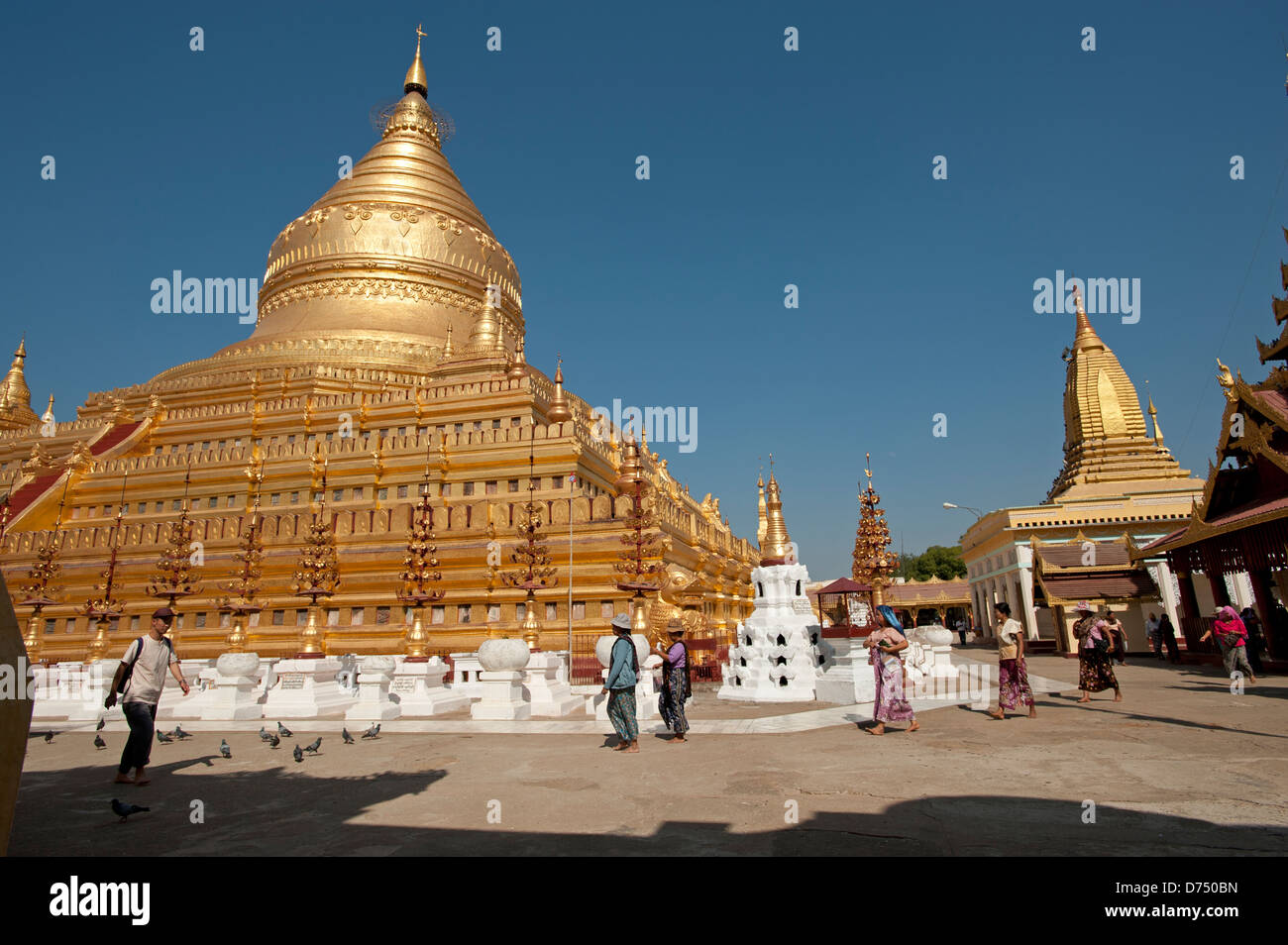 Les habitants de la Birmanie à pied passé le grand dôme d'or de la Pagode Shwezigon Bagan Myanmar (Birmanie) Banque D'Images