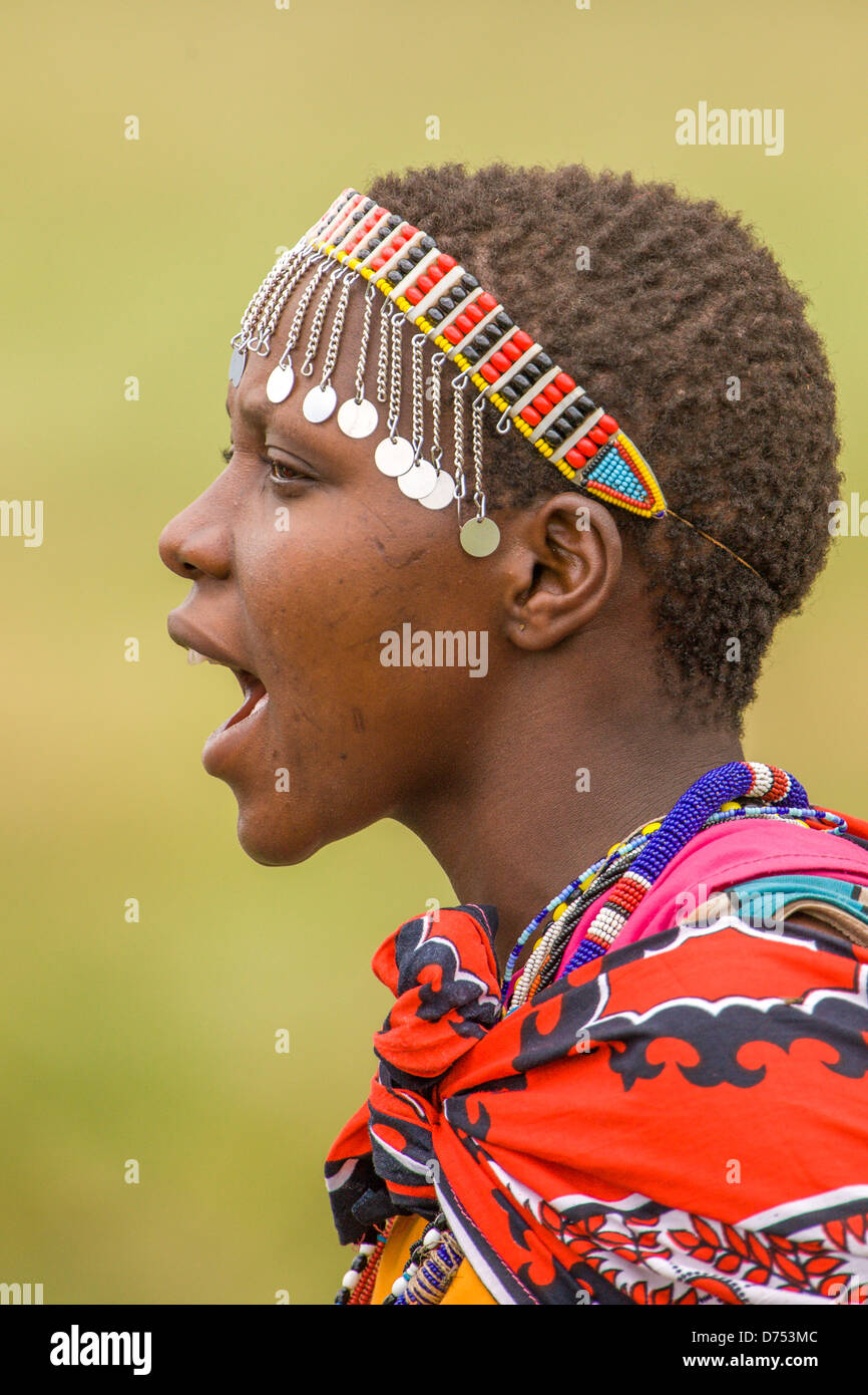 Une jeune femme Massaï chante passionnément en tenue traditionnelle, mettant en valeur un patrimoine culturel dynamique et l'esprit de l'Afrique de l'est. Banque D'Images