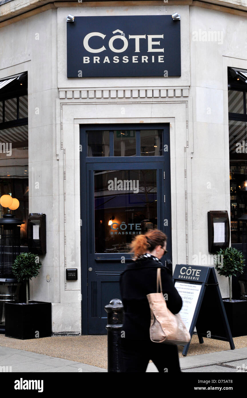 Une femme marche dernières côte Brasserie, un bistro français à Londres, au Royaume-Uni. Banque D'Images