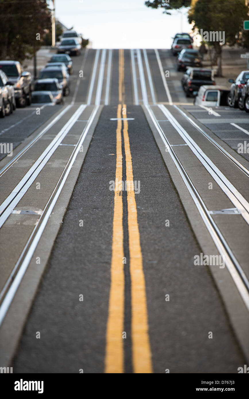 Hyde Street San Francisco // SAN FRANCISCO — des pistes de téléphérique en métal sont intégrées dans le trottoir escarpé de Hyde Street à son intersection avec Filbert Street dans le quartier de North Beach. La ligne de téléphérique Hyde Street fait partie du système historique de téléphériques de San Francisco, qui a fonctionné en continu depuis la fin du XIXe siècle. La pente raide de Hyde Street, comme beaucoup de collines de San Francisco, nécessite le mécanisme de préhension unique du système de téléphérique pour tirer les voitures vers le haut des pentes qui seraient impossibles pour les tramways conventionnels. Le quartier de North Beach, situé sur la Banque D'Images