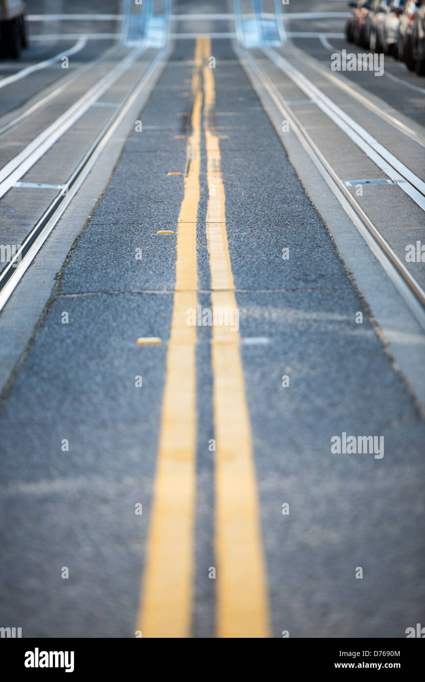 Pistes de téléphérique Steep Street San Francisco // SAN FRANCISCO, Californie — les pistes de téléphérique sont encastrées dans le trottoir de l'une des rues escarpées de San Francisco. Le système de téléphérique de la ville, qui a commencé à fonctionner en 1873, utilise un réseau de câbles souterrains pour tirer les voitures le long du terrain difficile de la ville. Les téléphériques de San Francisco sont parmi les rares systèmes de téléphériques à commande manuelle encore utilisés dans le monde entier et ont été désignés National Historic Landmark en 1964. La topographie abrupte qui a nécessité ce système de transport est une caractéristique déterminante de San Franc Banque D'Images