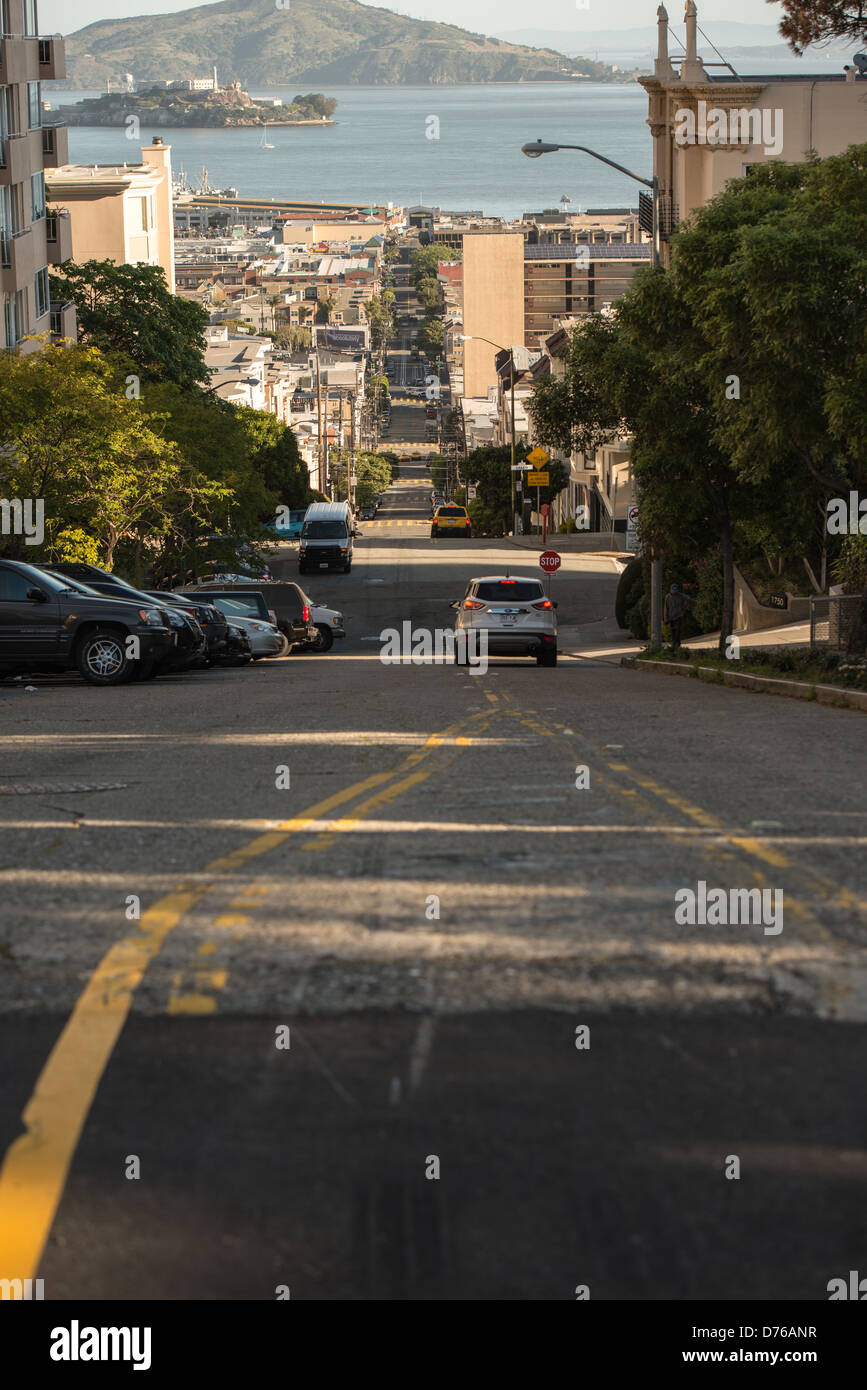 Taylor Street Steep Hill Alcatraz View San Francisco Californie // SAN FRANCISCO, Californie — Taylor Street descend abruptement à travers le quartier de North Beach à San Francisco, offrant une vue sur l'île d'Alcatraz et la baie de San Francisco. La rue fait partie des célèbres artères escarpées de la ville qui caractérisent le terrain vallonné de San Francisco. North Beach, situé sur le front de mer nord, est largement connu comme le quartier italo-américain de la ville et le centre historique de la culture Beat Generation. L'île d'Alcatraz, visible au loin de l'autre côté de la baie, a servi de prison fédérale de 1934 à 196 Banque D'Images