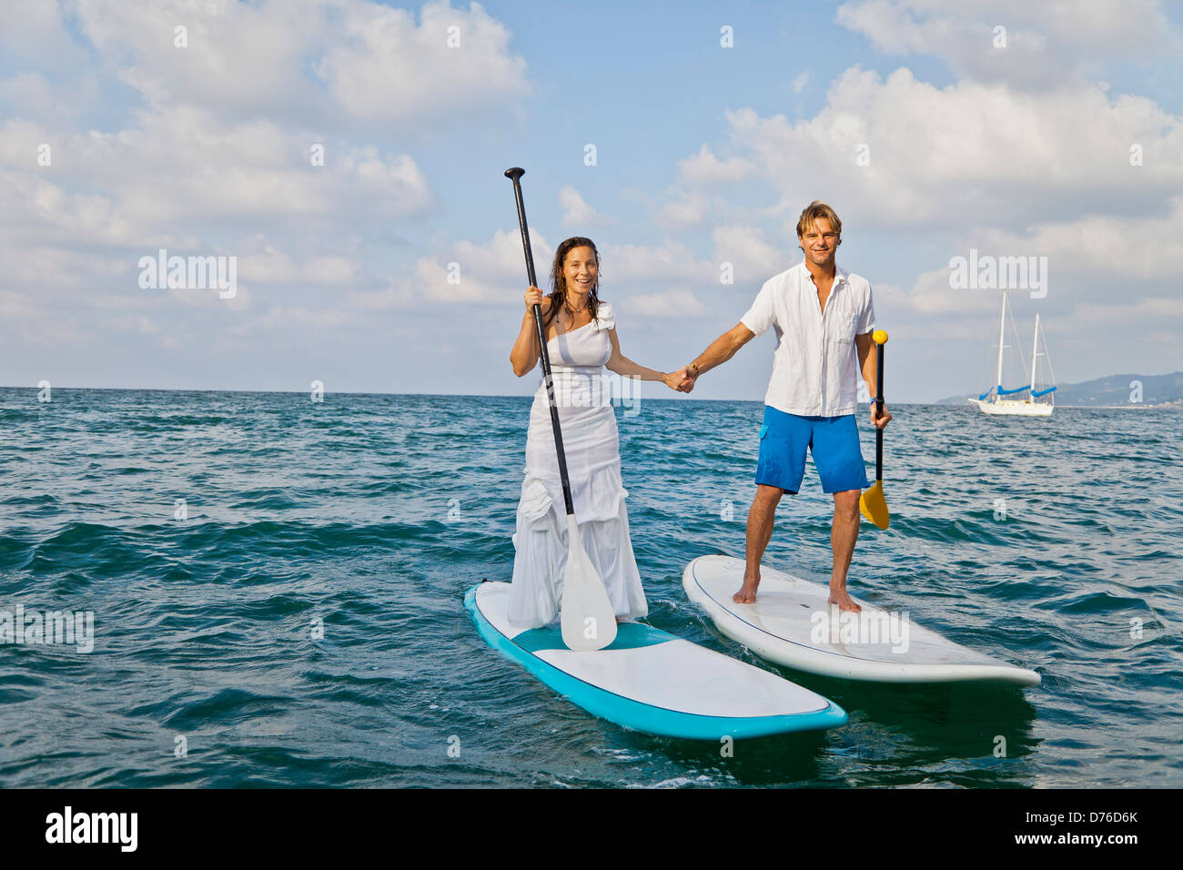 Habillé man and woman riding paddle boards Banque D'Images