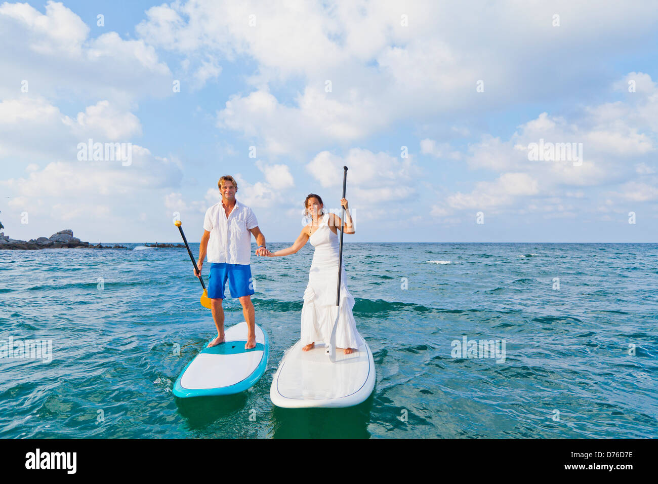 Habillé man and woman riding paddle boards Banque D'Images