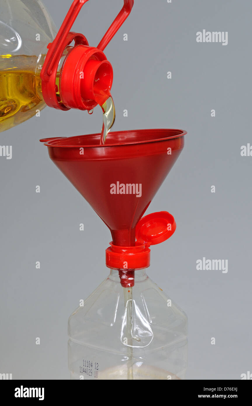 Verser l'huile d'olive à travers un entonnoir dans une bouteille plus  petite sur un arrière-plan gris Photo Stock - Alamy