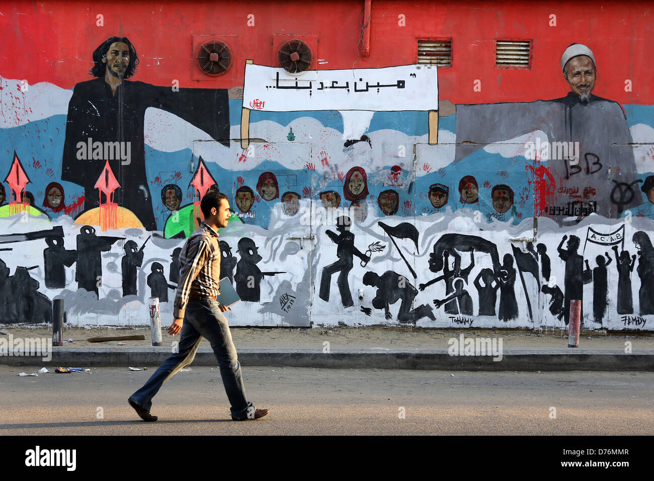 Homme marche devant une fresque révolutionnaire sur un mur des martyrs près de la place Tahrir au Caire. Banque D'Images