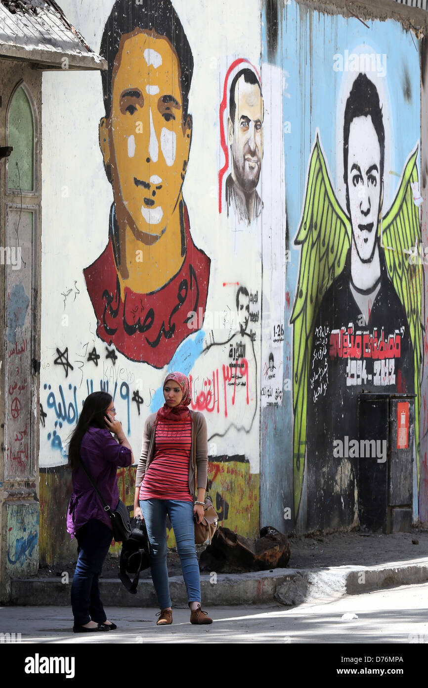 La femme en face d'une peinture murale révolutionnaire sur un mur des martyrs près de la place Tahrir au Caire. Banque D'Images