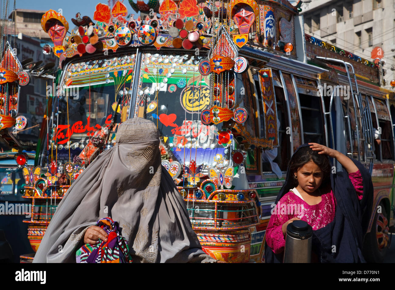 Une scène de rue la vie quotidienne avec une femme en burqa et bus colorés à Peshawar, au Pakistan. Banque D'Images