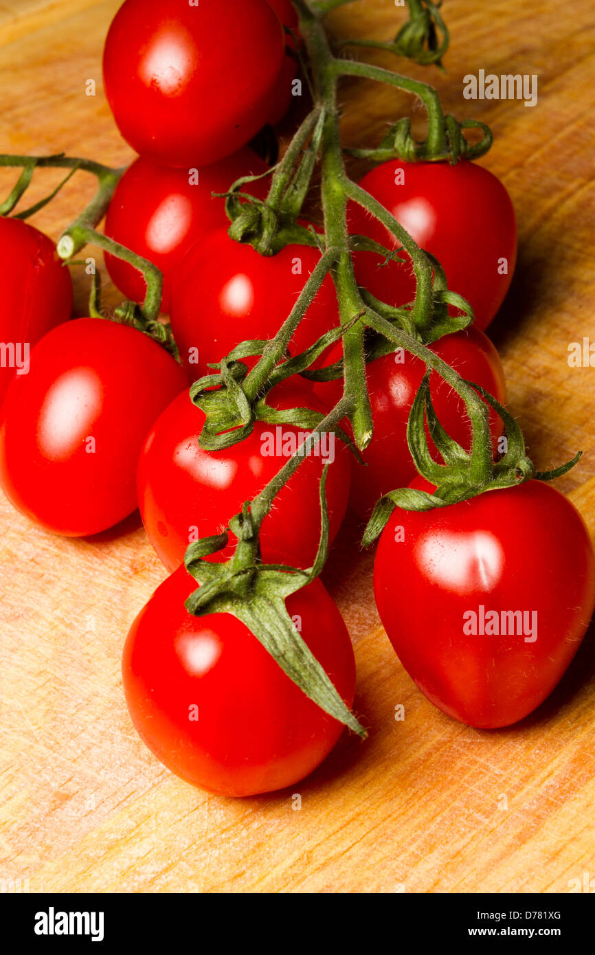 Tomates fraîches mûries sur vigne, Sunstream variété, sur une planche à découper en bois, England, UK Banque D'Images