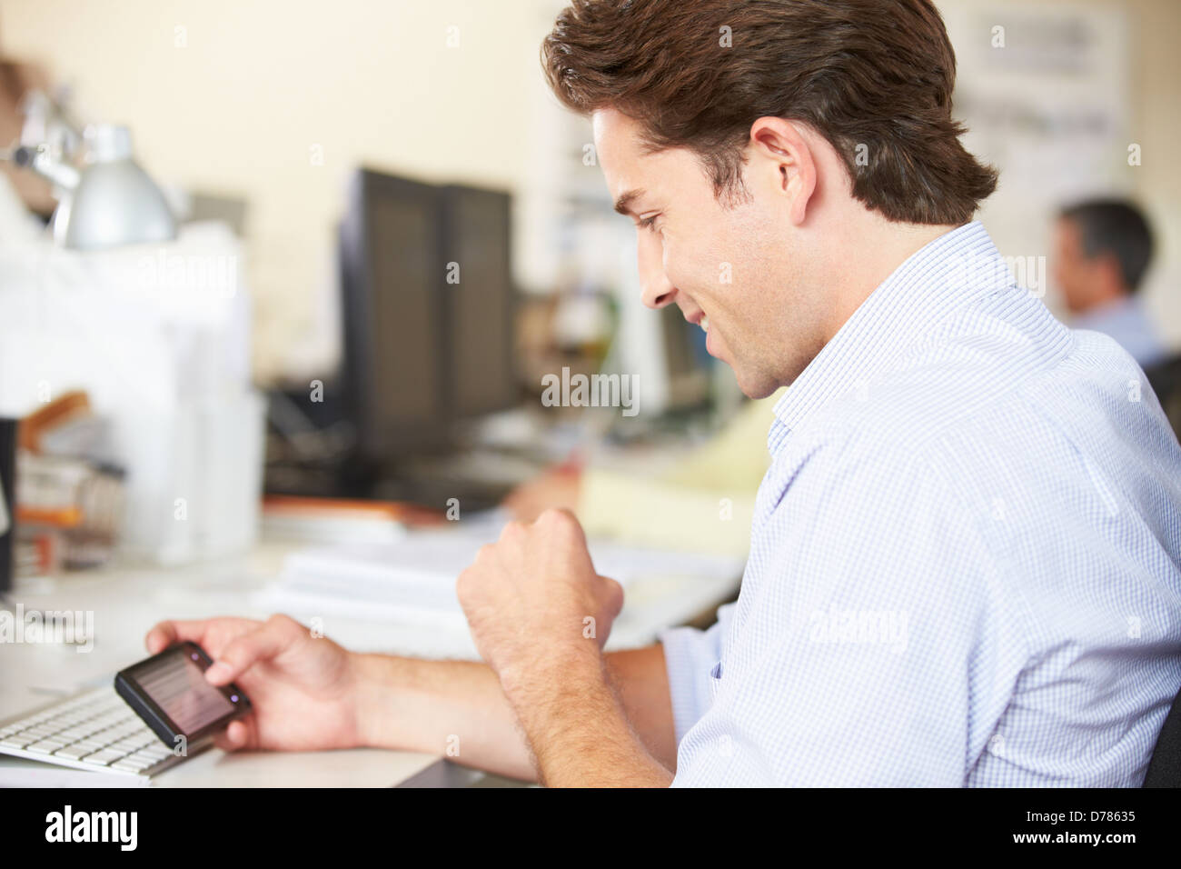 L'homme à l'aide de téléphone mobile à 24 dans l'état Occupé Creative Office Banque D'Images