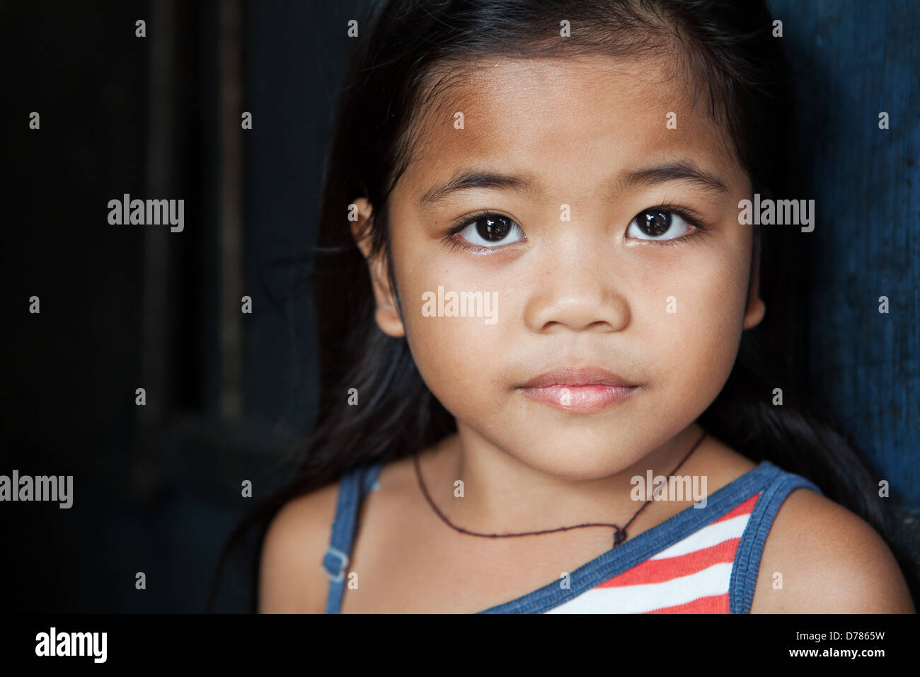 Portrait enfant asiatique - jeune fille des Philippines contre mur - lumière naturelle Banque D'Images