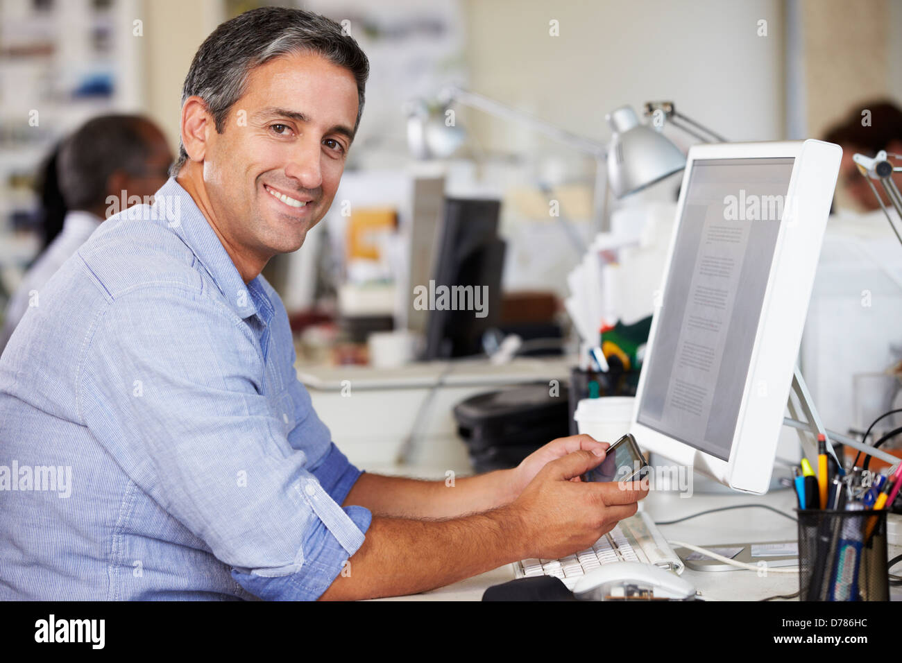 L'homme à l'aide de téléphone mobile à 24 dans l'état Occupé Creative Office Banque D'Images