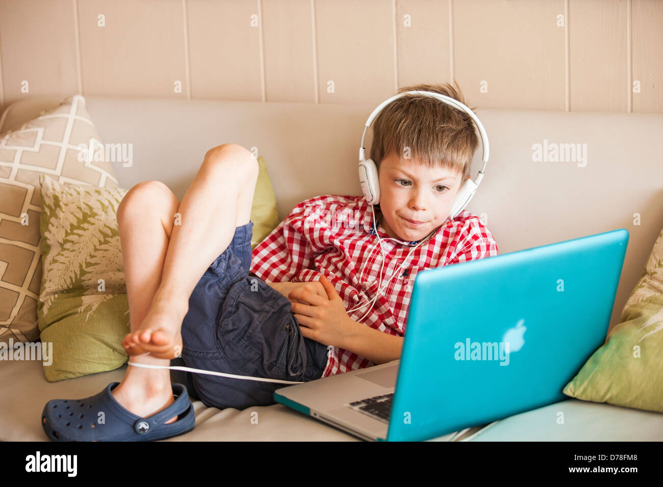 Boy using laptop et écouteurs Banque D'Images