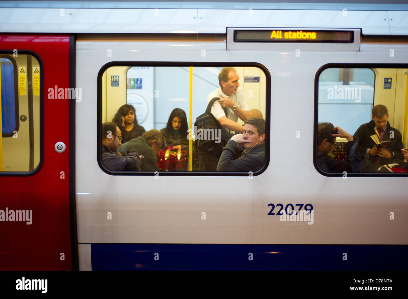 Les navetteurs sur un train de tube, avec un homme portant un casque en regardant par la fenêtre. Banque D'Images