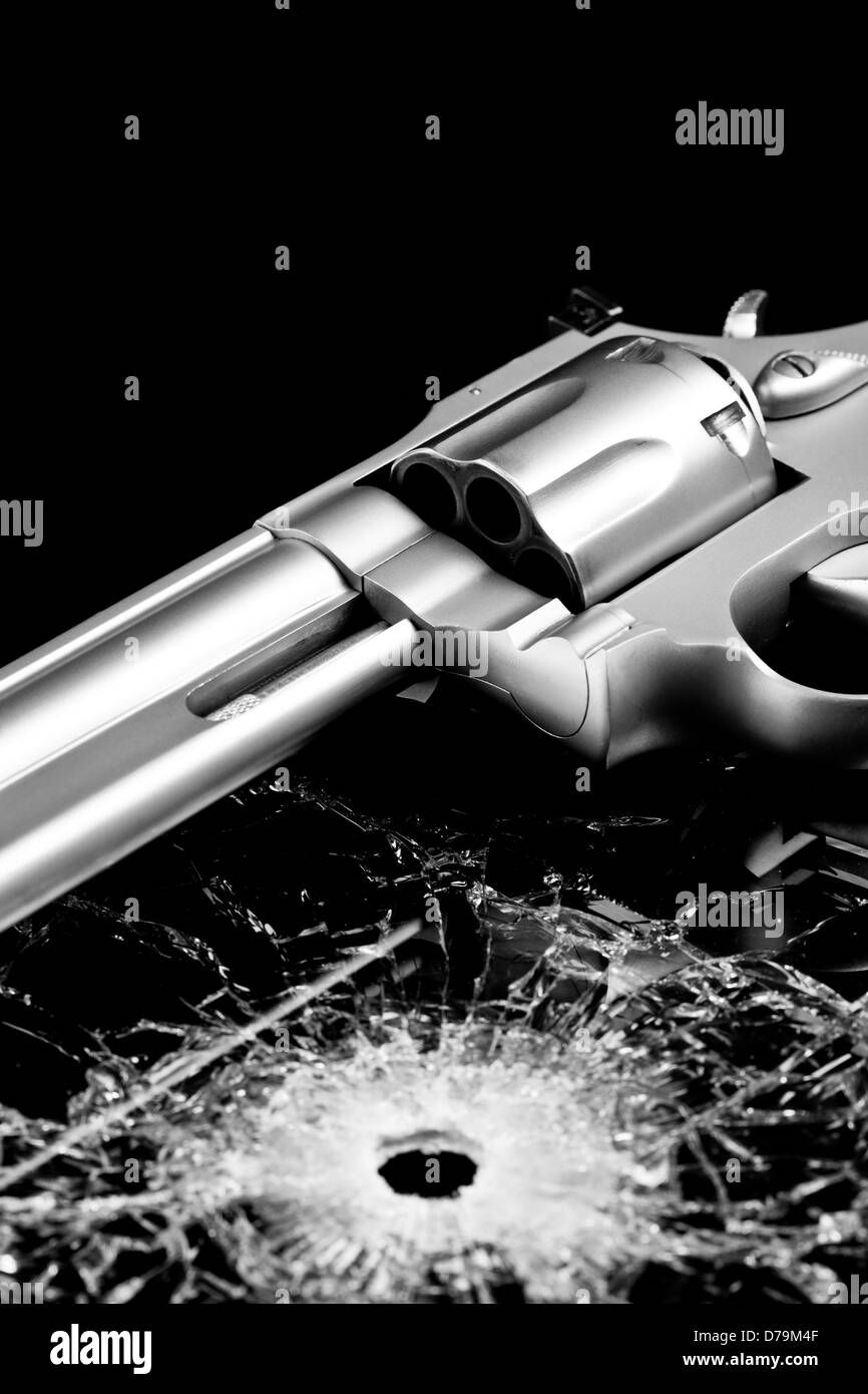 Pistolet avec trou de balle en verre isolé sur fond noir - revolver moderne de verre brisé Banque D'Images