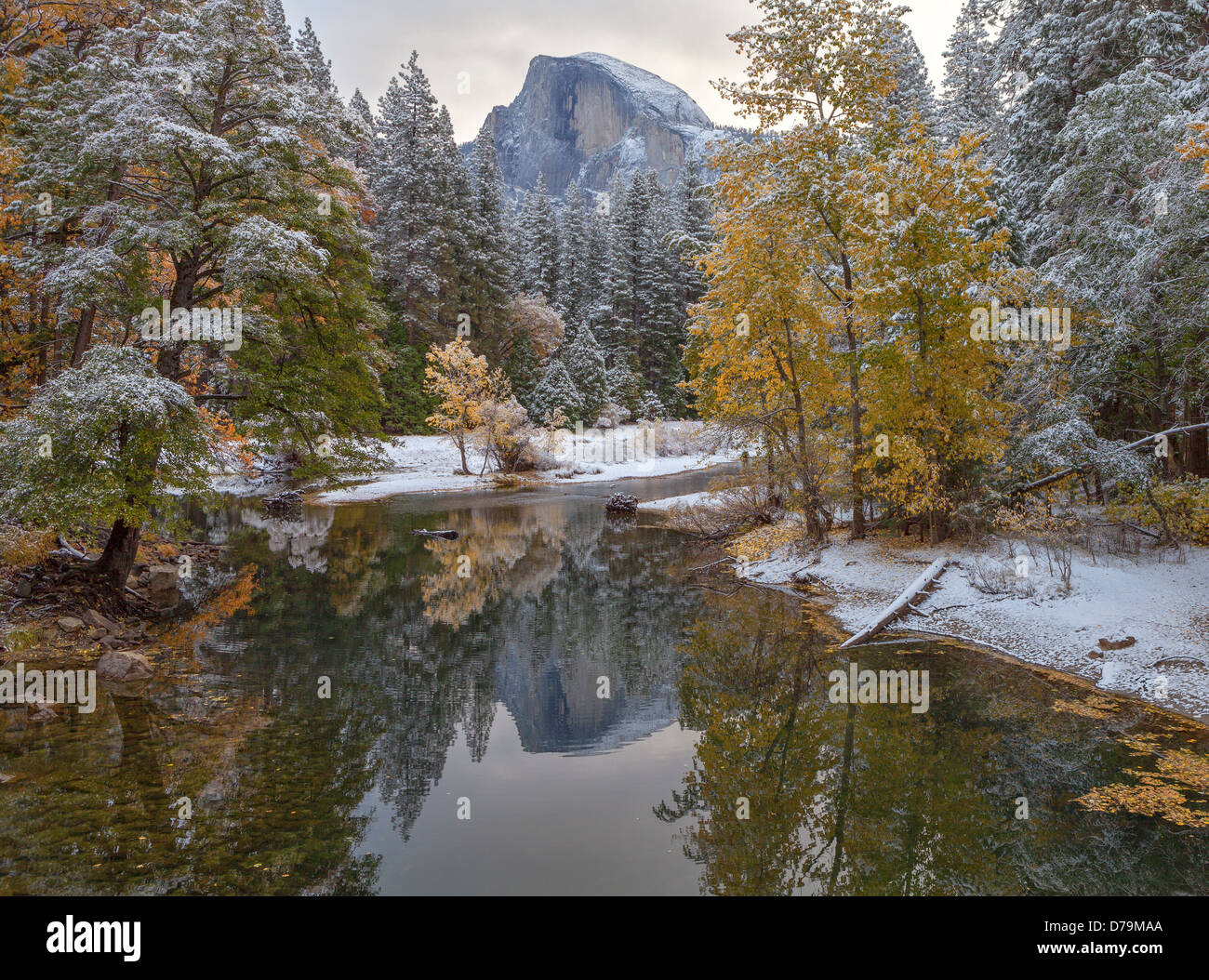 Yosemite National Park, Californie : Demi Dôme réfléchissant sur la rivière Merced avec de la neige fraîche le long des rives Banque D'Images