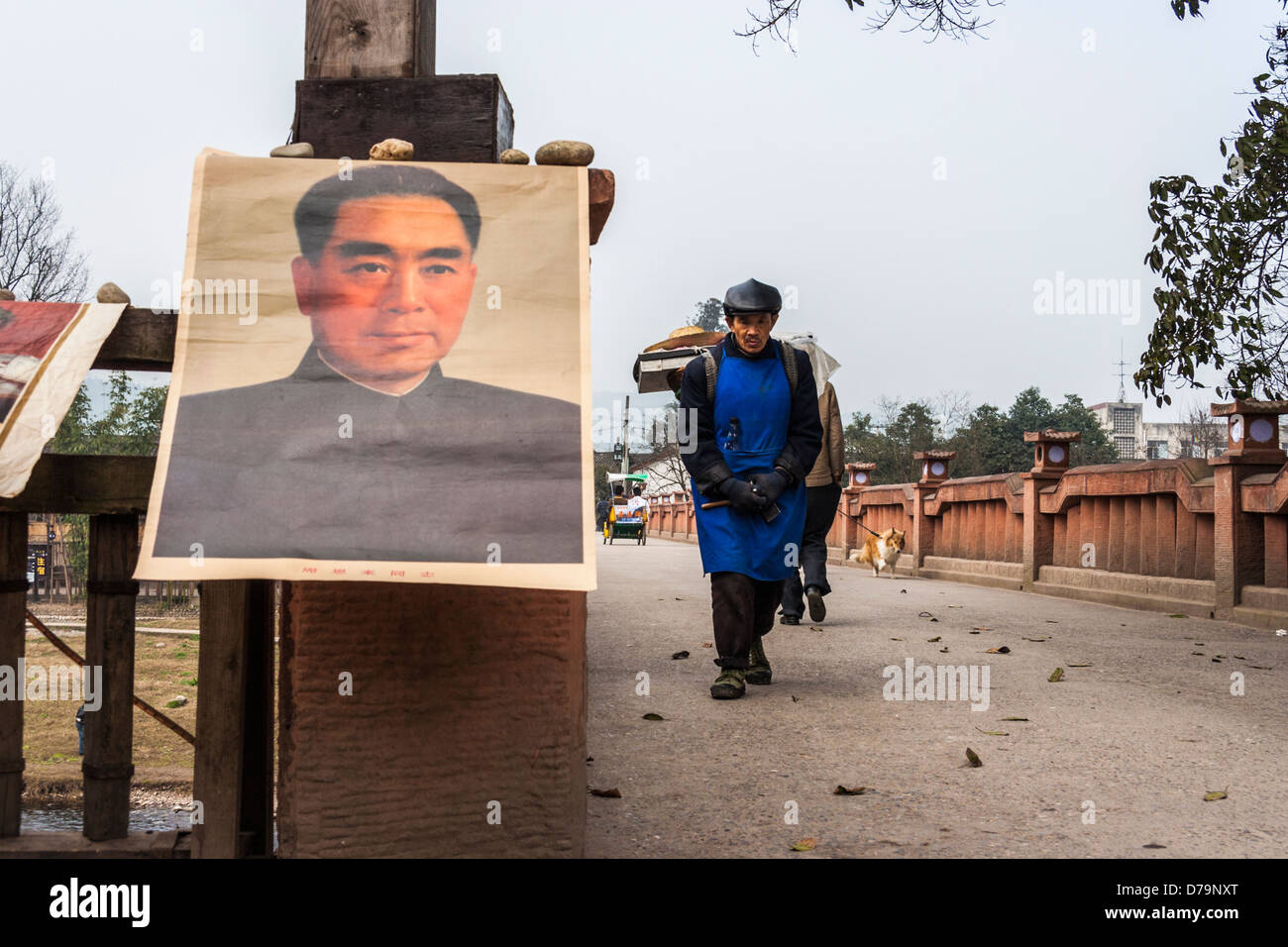 Artisan chinois marche sur un pont avec de vieilles affiches Mao vendus comme souvenirs à Pingle village, près de Chengdu, Sichuan, Chine Banque D'Images