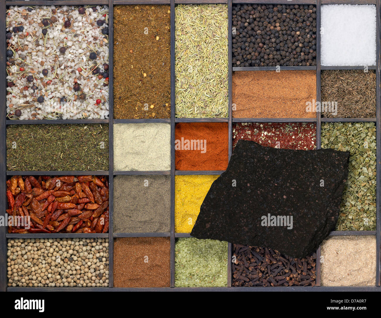 Beaucoup de différentes épices dans un cadre en bois foncé avec une pierre en bois foncé sur elle, vu de dessus Banque D'Images