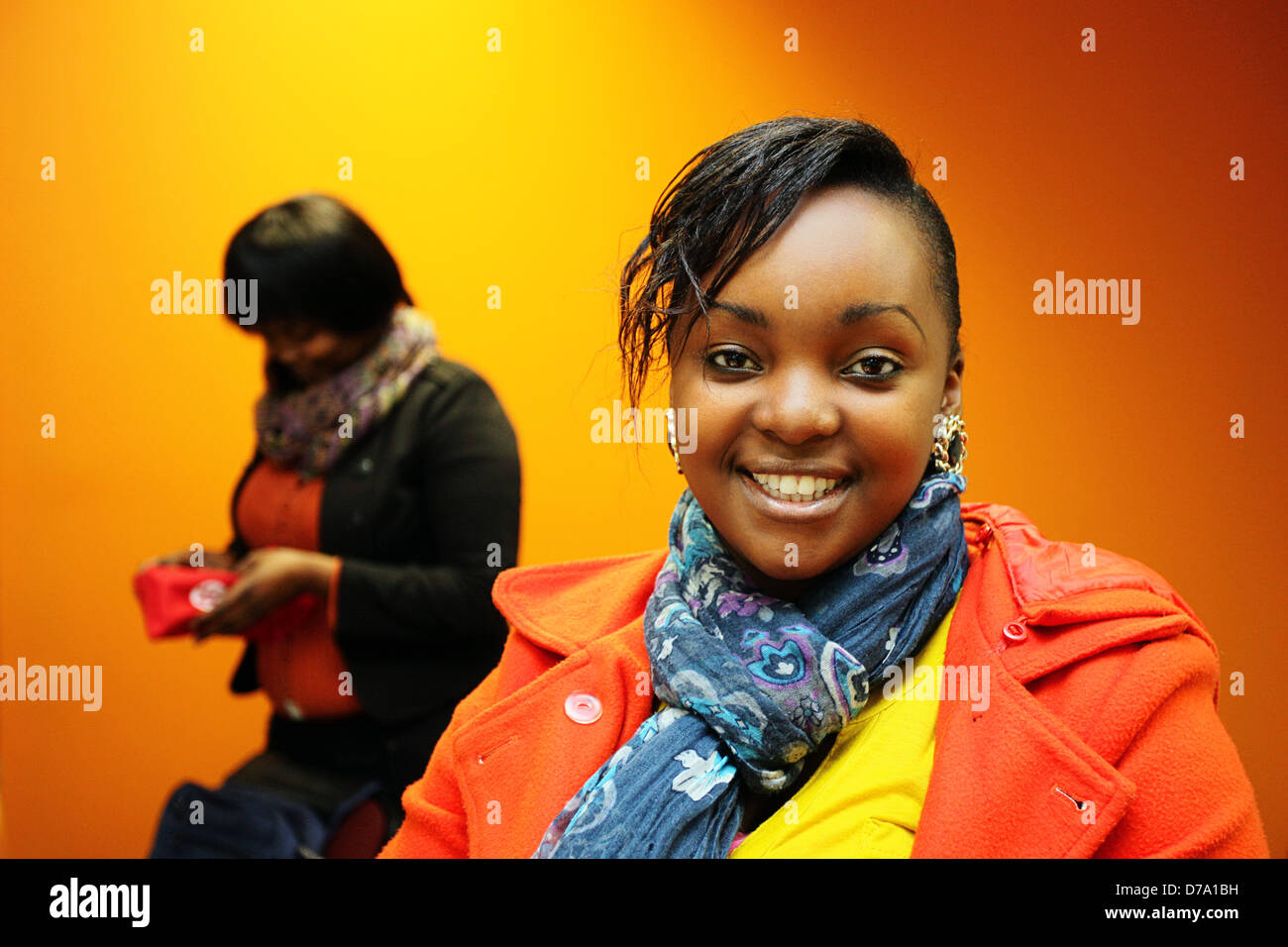 South African woman smiling contre un fond orange et jaune. Banque D'Images