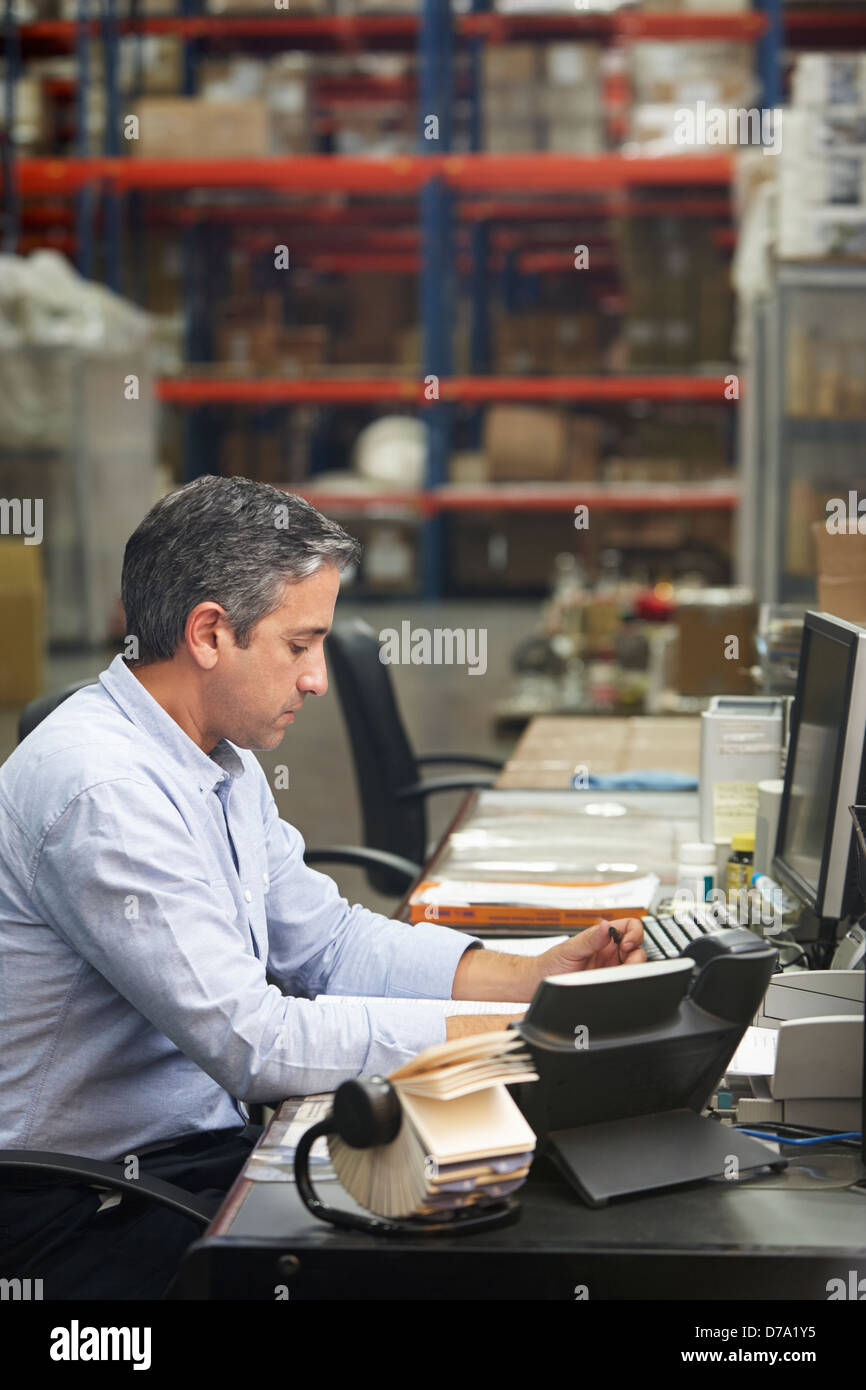 Manager Working at Desk In Warehouse Banque D'Images