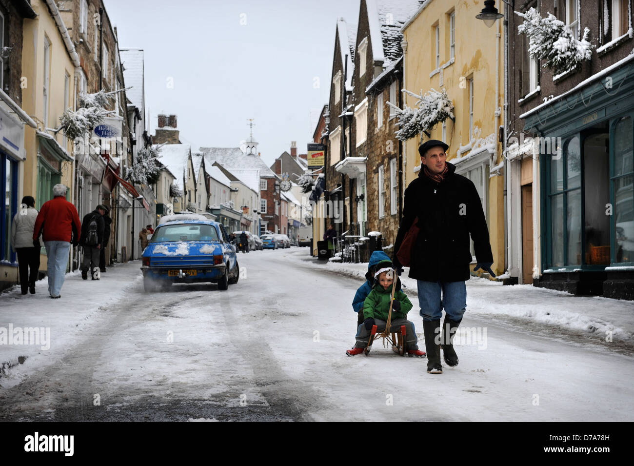 Les traits d'un père à ses enfants sur une luge un snow bound High Street, dans le Gloucestershire, Wotton-Under-Edge UK Banque D'Images