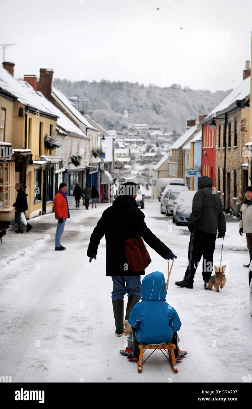 Les traits d'un père à ses enfants sur une luge un snow bound High Street, dans le Gloucestershire, Wotton-Under-Edge UK Banque D'Images