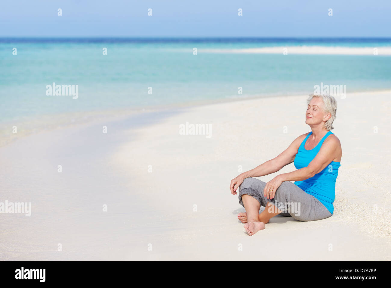 Senior Woman Meditating On Belle Plage Banque D'Images
