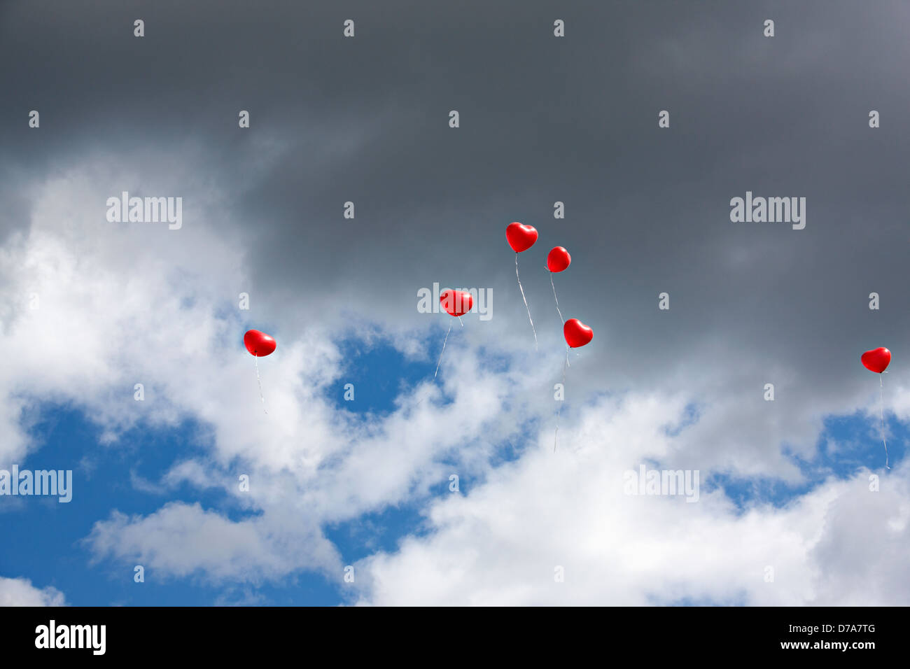 Ballons coeur rouge avec l'air nuageux ciel bleu Banque D'Images