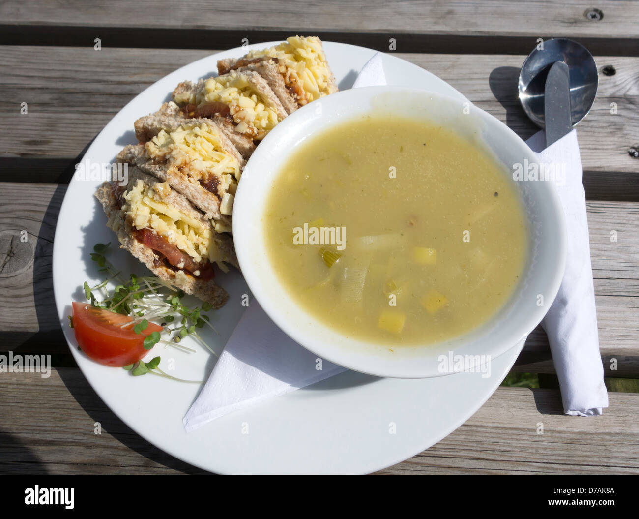 Café le déjeuner un bol de soupe aux poireaux et pommes de terre avec un fromage Cheddar et sandwich cornichon à l'extérieur, au soleil Banque D'Images