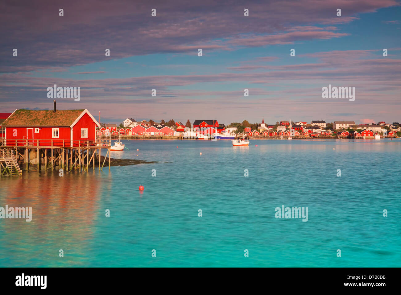 Cabane rorbu typique rouge avec toit de chaume en ville de reine sur les îles Lofoten en Norvège éclairées par le soleil de minuit Banque D'Images