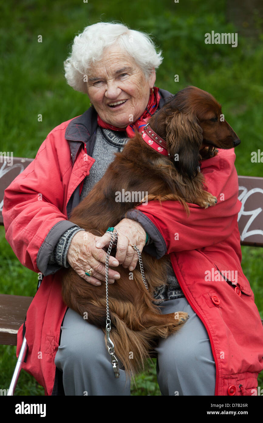 Une femme âgée avec un chien sur un banc, vieille femme vieillissant, chien femme senior, Hug 70s retraité, pensionné sur un banc de jardin chien femme âgée Banque D'Images