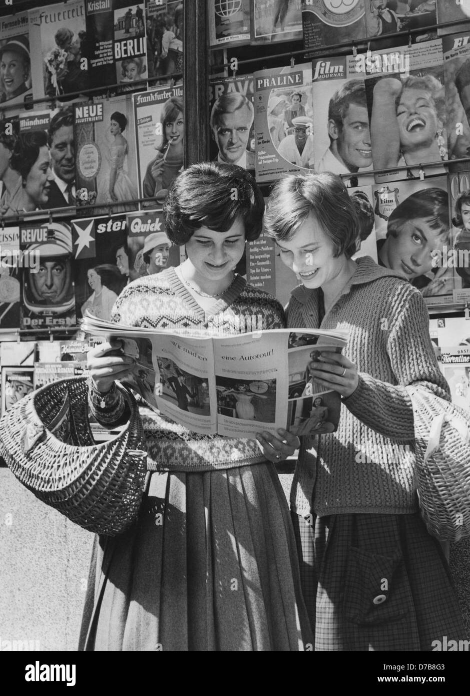 Deux jeunes femmes lire un magazine en face d'un kiosque dans les années 50. Banque D'Images