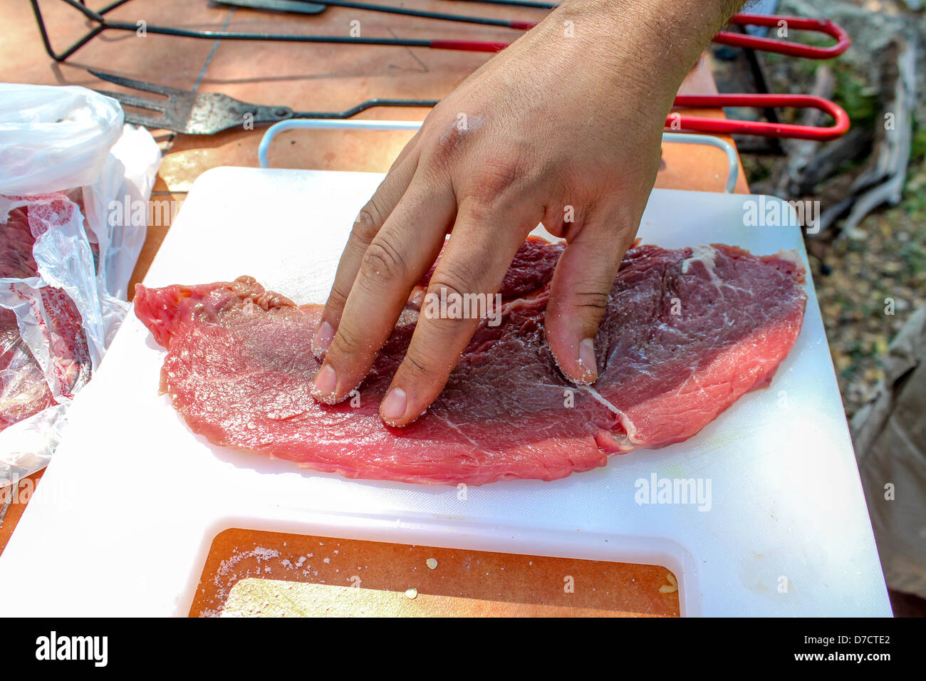 Un homme le salage de la viande avant la cuisson Banque D'Images