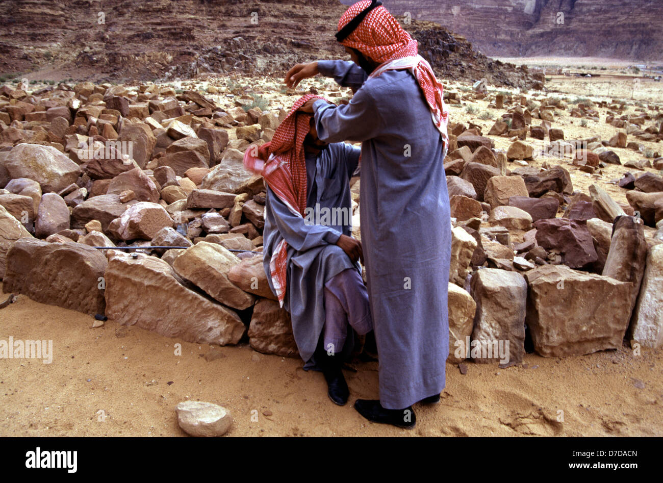 Bédouins portant un keffieh à carreaux blancs et rouges et des robes traditionnelles dans le désert de Wadi Rum connu aussi sous le nom de la vallée de la lune, dans le sud de la Jordanie Banque D'Images