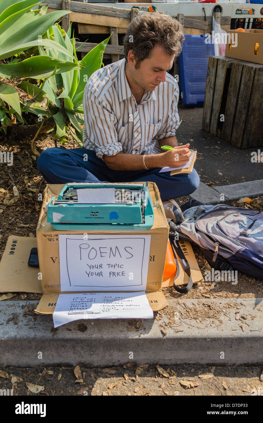 Un homme âgé de 25 à 30 ans est assis sur le sol avec sa machine à écrire Smith-Corona sur une boîte en carton d'origine vente de poèmes. Banque D'Images