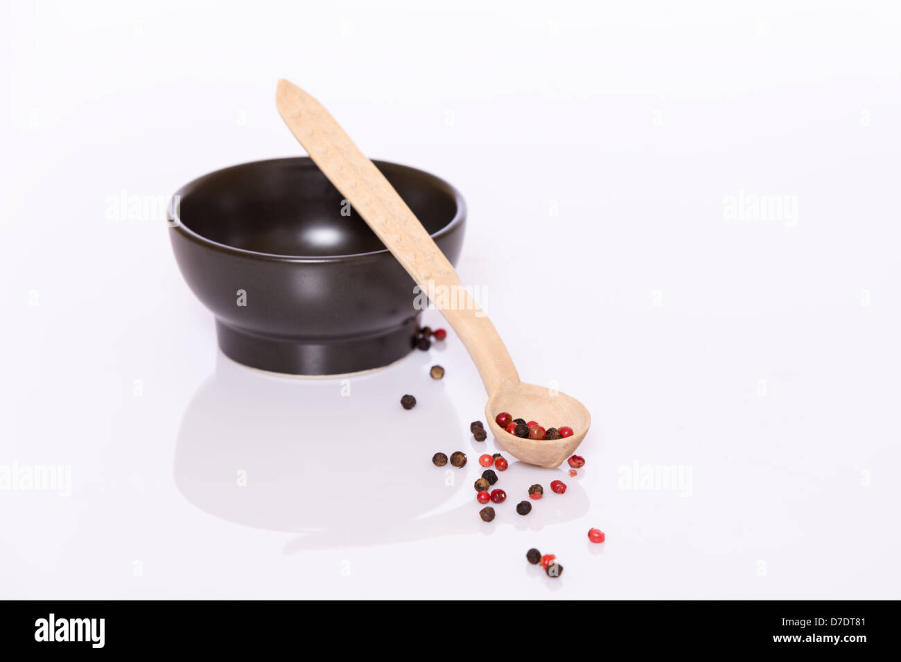 Poivre rose et noir dans la cuillère en bois et en noir bol Banque D'Images