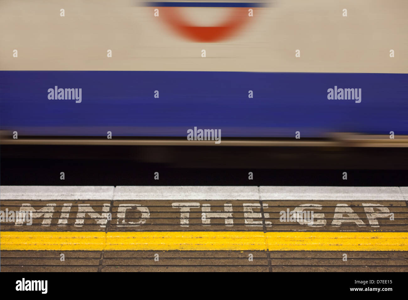 La station de métro Bank 'Mind l'écart' signe peint sur la plate-forme de station avec fast moving train de tube à l'arrière-plan. Banque D'Images