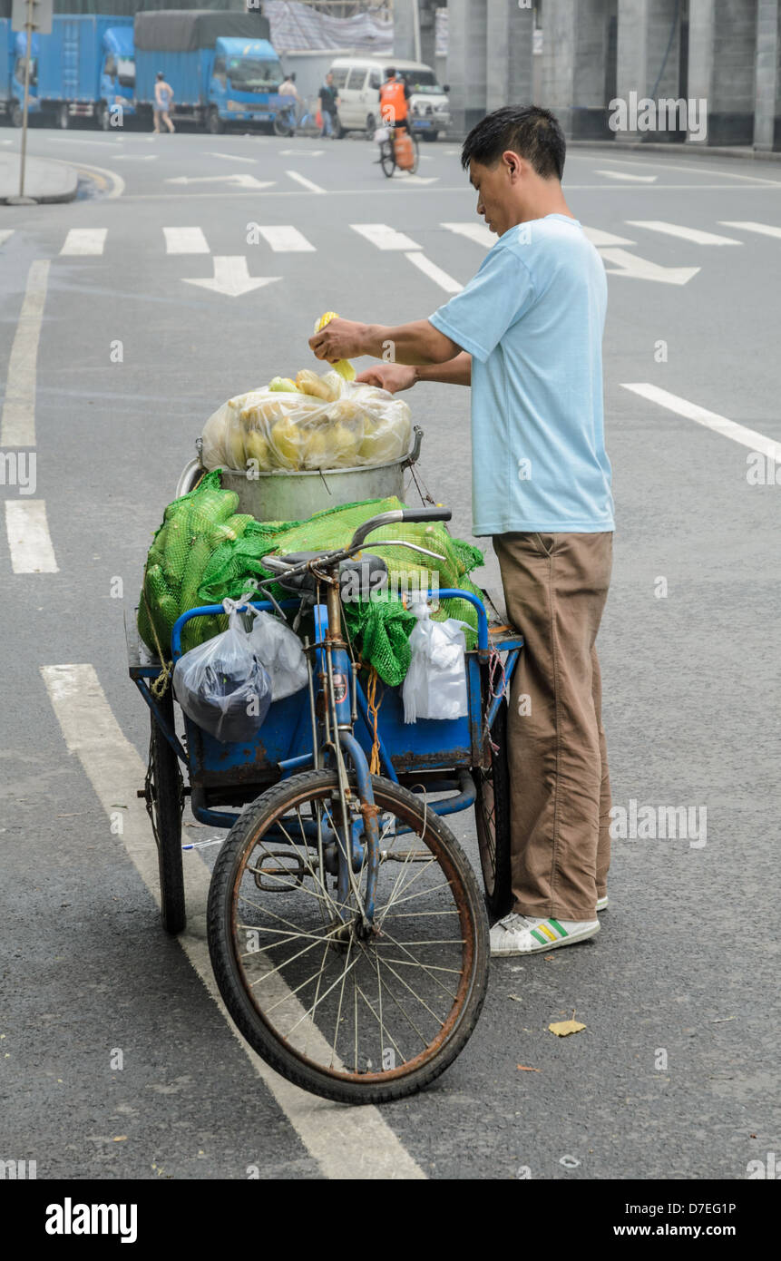 Vendeur de rue chinois comment préparer les légumes pour la vente de son tricycle. Banque D'Images