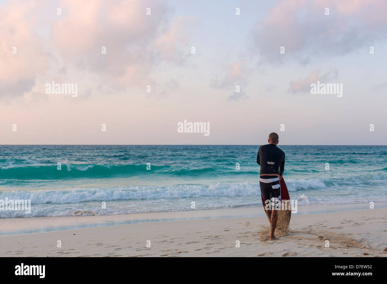 Surfeur homme debout sur une plage et donnant sur la mer Banque D'Images