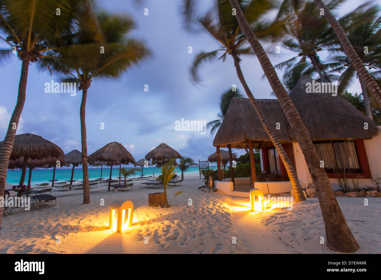 Hébergement de style cabana sur la plage entourée de palmiers à l'aube Banque D'Images