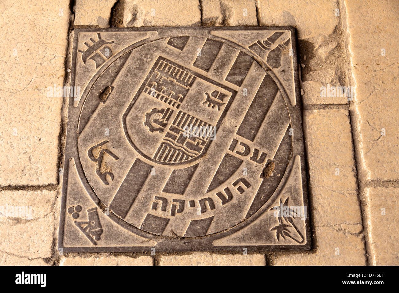 Couvercle d'égout emblème ancienne ville Acco (Acre en Israël) inscrits sur elle. texte en hébreu, arabe trnaslates à 'ancienne' Acco. Banque D'Images