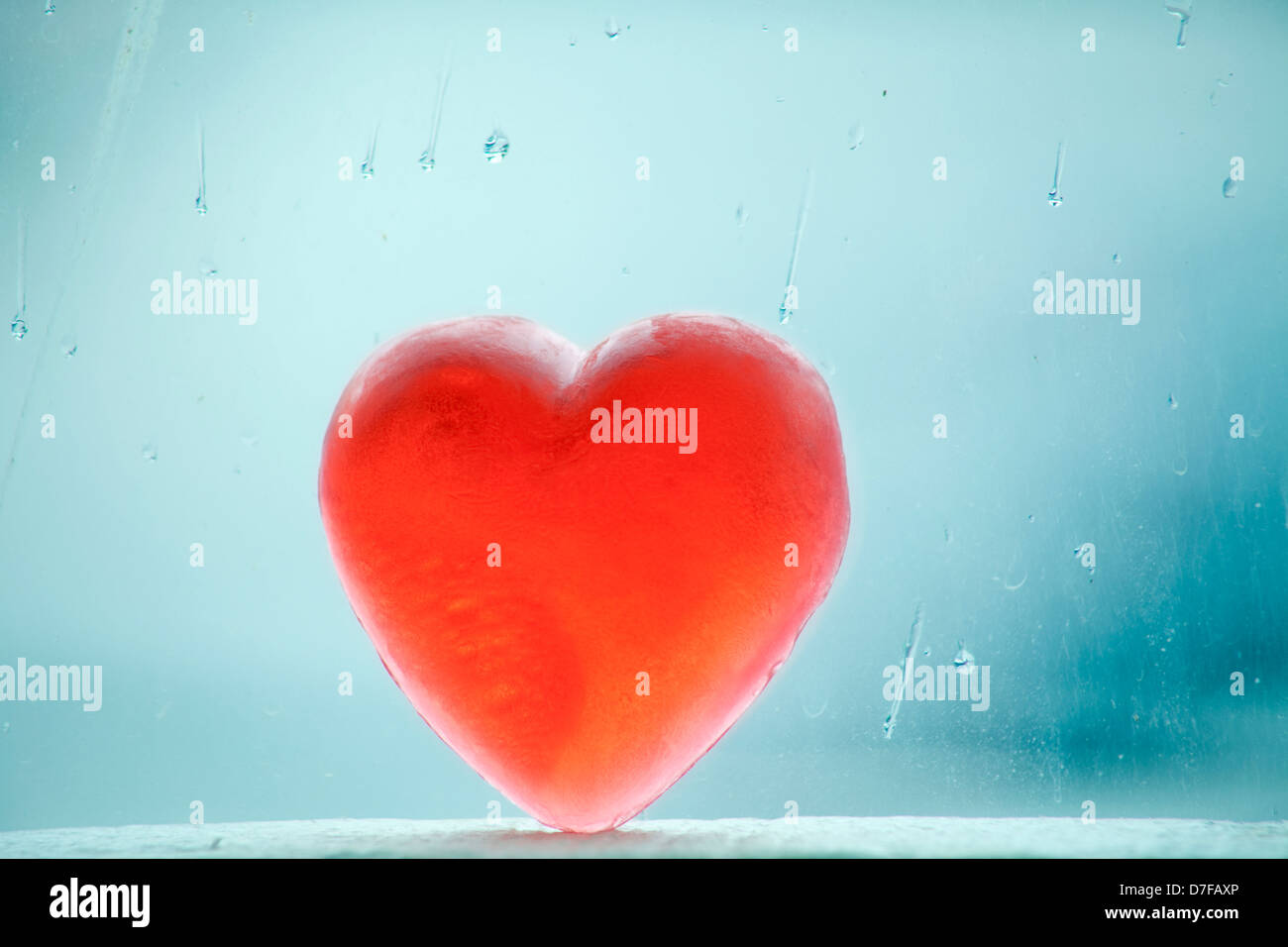 Savon en forme de coeur s'appuyant sur une fenêtre couverte de gouttes de pluie sur une journée d'hiver. Banque D'Images