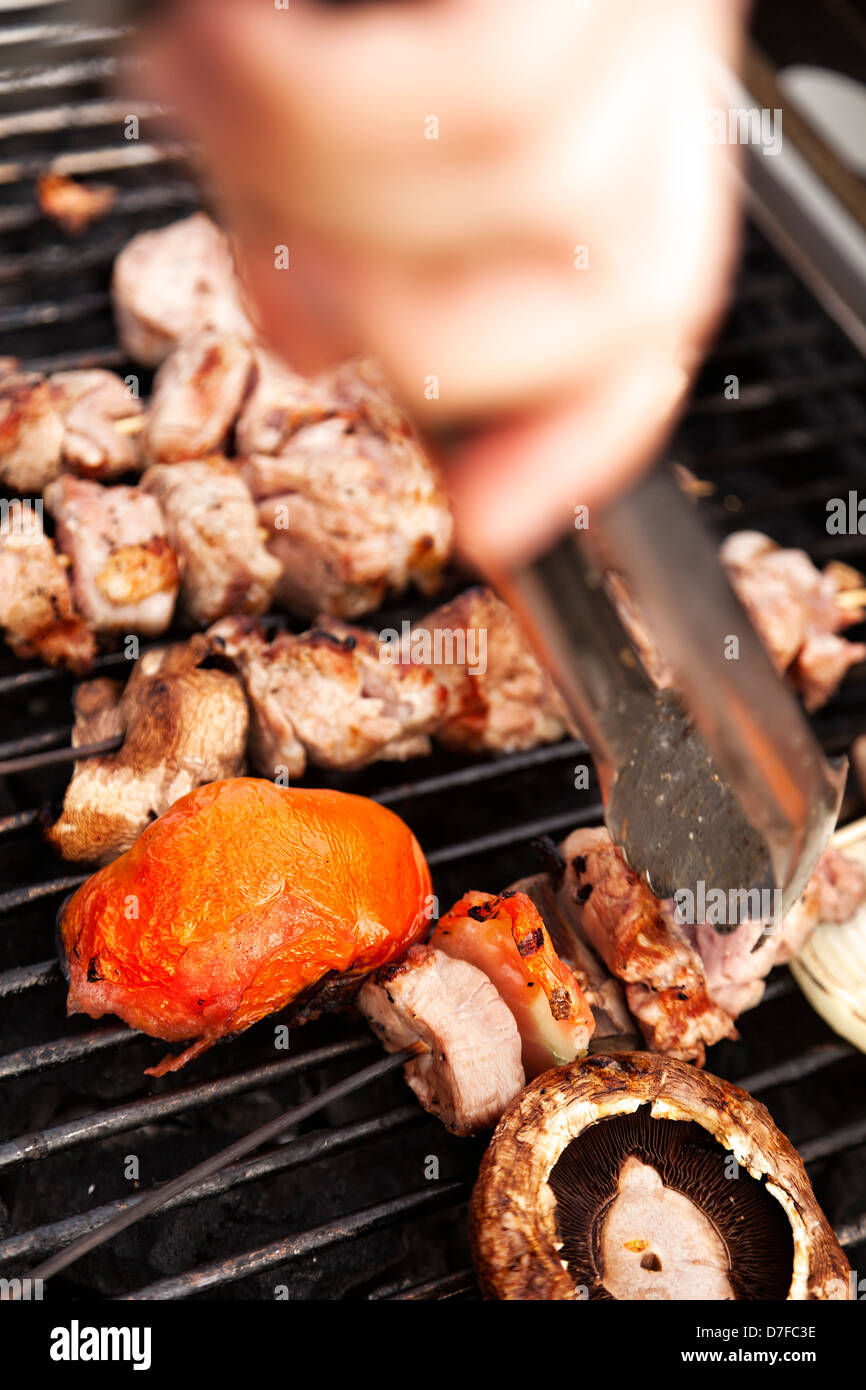 Poulet aux champignons portobello asymétrique tomates préparation sur une piscine barbecue très floues main est un tournant skewes Banque D'Images