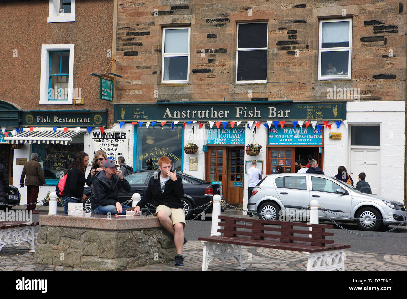 Groupe de jeunes gens de l'extérieur de la consommation de poisson et frites à partir de l'primé d'Anstruther Fish Bar dans le Fife Ecosse Banque D'Images