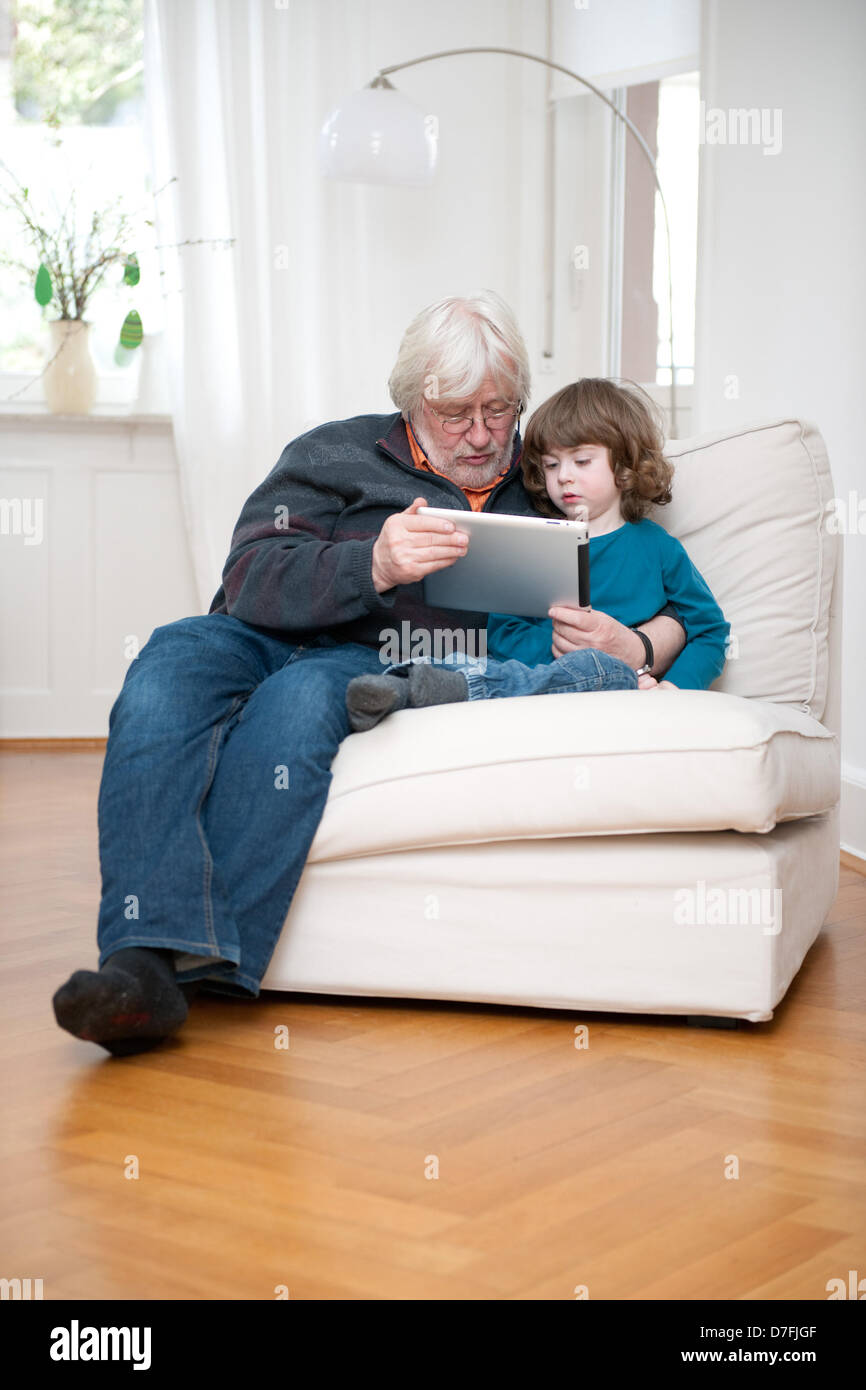 Un grand-père est montrant son petit-enfant quelque chose sur l'ipad. Banque D'Images