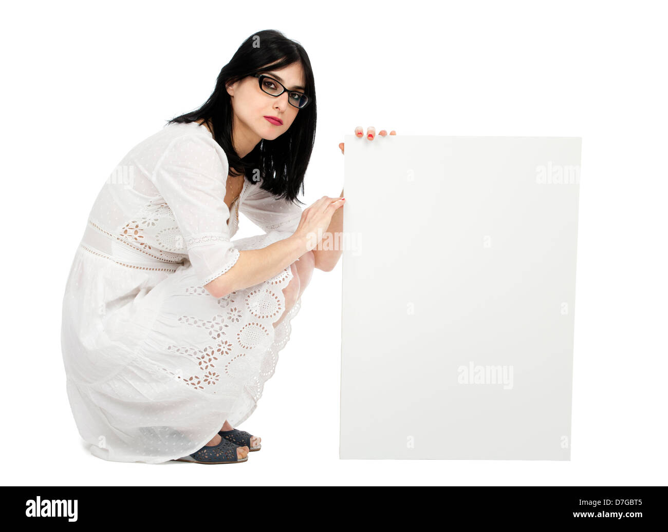Un adulte (début 30's) black haired caucasian woman wearing jolie robe d'été blanche. Elle est accroupi holding blank sign next Banque D'Images
