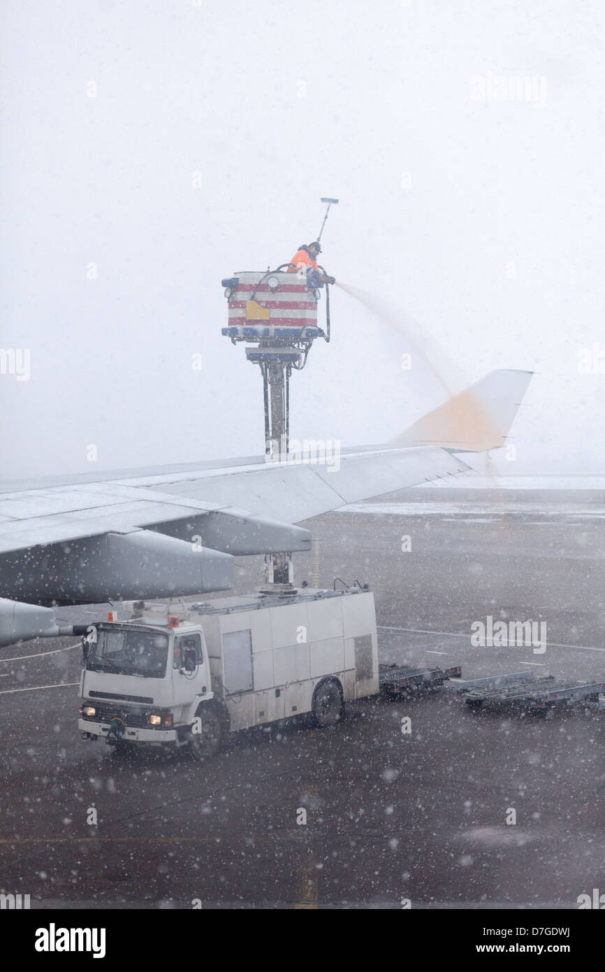 Personnel technique le dégivrage des avions ailes avec fluide pendant une forte tempête de neige. Banque D'Images