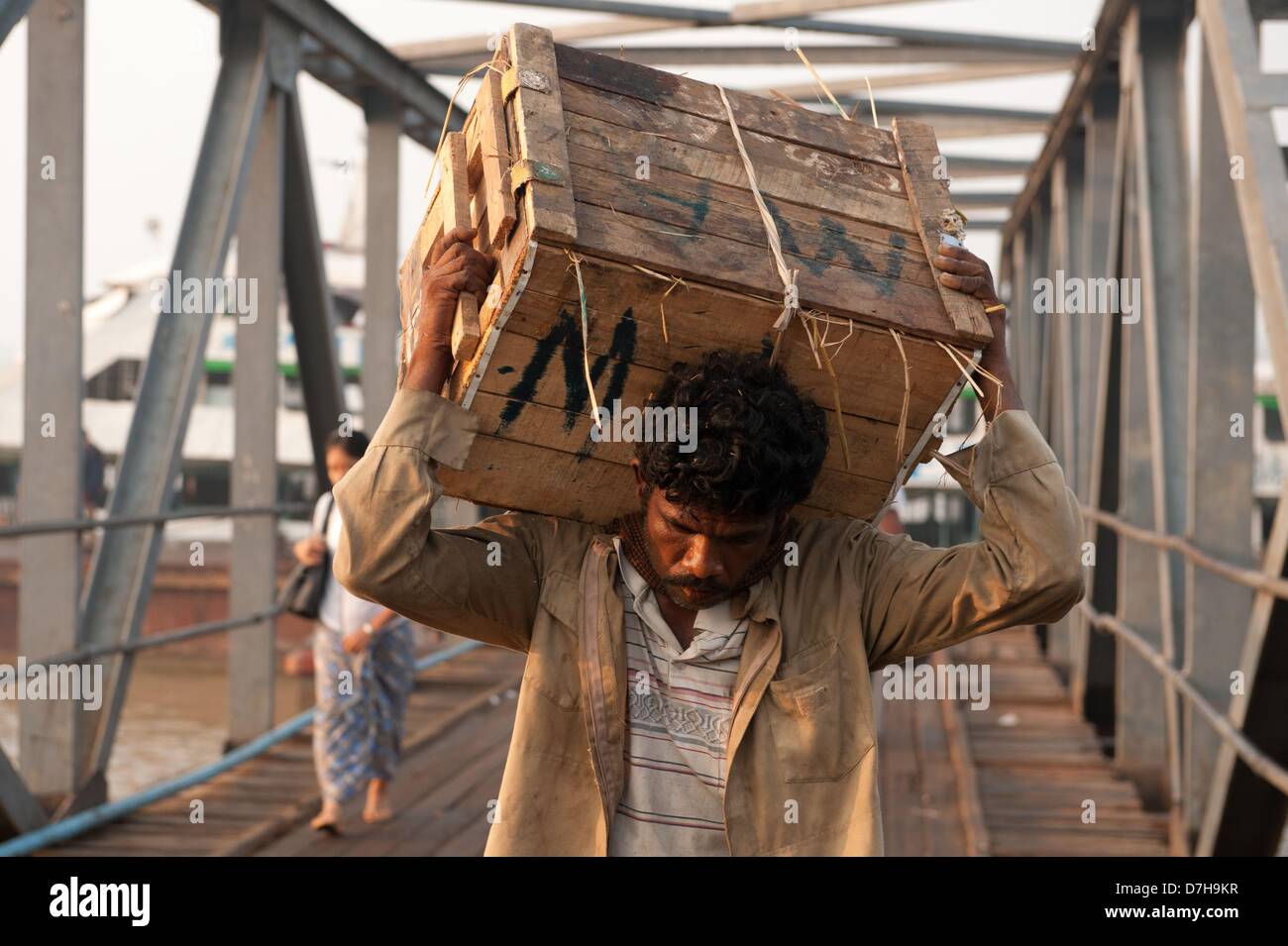 Un homme porte une boîte en bois sur un pont au péché Oh Dan jetée à Rangun, Myanmar, 12 avril 2013. Photo : Sebastian Kahnert Banque D'Images