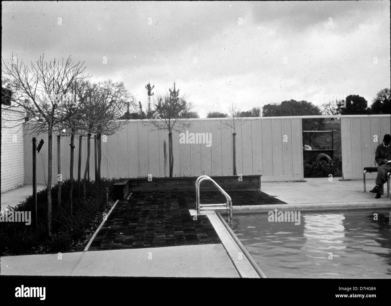 Une image sereine d'une cour en briques avec une piscine et un camion garé à proximité, suggérant un environnement détendu avec un patio extérieur, entouré d'arbres. L'image évoque une scène extérieure paisible au charme rustique. Banque D'Images